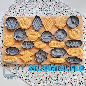 Può includere: Un set di 20 stampini per biscotti con vari loghi di auto, tra cui Volkswagen, BMW, Audi, Ford e altri. Gli stampini sono in plastica grigia e sono disposti su una superficie di legno. Il testo "STL/DIGITAL FILE" è visibile nella parte inferiore dell'immagine.