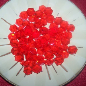 May include: A white plate with a pile of red, clear, candy shaped like gemstones.