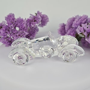 May include: A clear crystal figurine of a vintage car. The car is detailed with a windshield, headlights, and wheels.