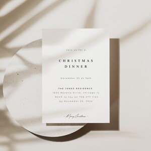 Könnte beinhalten: Eine minimalistische Weihnachtsdinner-Einladung mit weißem Text auf weißem Hintergrund. Die Einladung enthält Datum, Uhrzeit, Ort und RSVP-Informationen. Der Text lautet: "Schließen Sie sich uns zu einem Weihnachtsessen an, am 25. Dezember um 17:00 Uhr, The Jones Residence, 1630 Revello Drive, Chicago IL, RSVP an Joy unter 708 277 1142 bis zum 25. November 2024. -Frohe Weihnachten- "