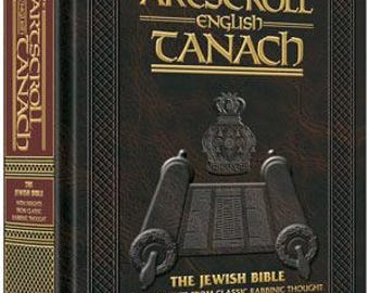 May include: A brown leather-bound book with gold lettering titled "The Artscroll English Tanach: The Jewish Bible with Insights from Classic Rabbinic Thought". The book is part of the Artscroll Series and features a stone edition label.