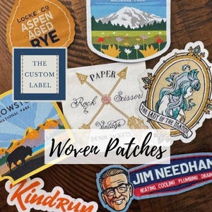 Puede incluir: Una colección de parches tejidos con varios diseños. Los parches incluyen texto como "Mount Rainier National Park", "Locke Co Aspen Aged Rye", y "Jim Needham Heating Cooling Plumbing Drain". Otros parches presentan ilustraciones y el texto "Paper Rock Scissors Vintage".
