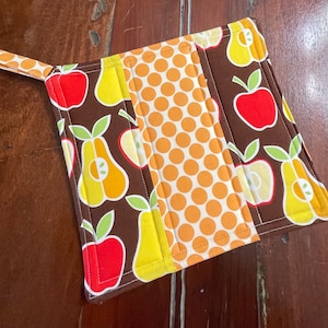 May include: A brown, yellow, and orange pot holder with a pear and apple design. The pot holder has a loop for hanging.