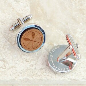May include: Silver cufflinks with a wooden inlay featuring a pair of crossed oars. One cufflink is engraved with the text "Happy Birthday Dad x".