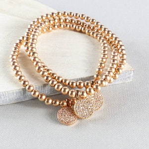 May include: Three gold beaded bracelets with small round charms set with clear stones.