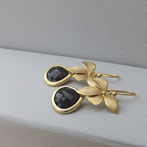 May include: Gold earrings with black gemstone drops and gold flower accents.