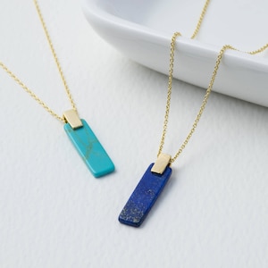 May include: Two gold necklaces with rectangular turquoise and lapis lazuli stone pendants.