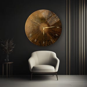 Puede incluir: Un gran reloj de pared dorado y redondo con números romanos cuelga de una pared gris oscuro. El reloj tiene un diseño de rayos de sol. Debajo, un sillón color crema con patas oscuras. A la izquierda, una pequeña mesa auxiliar con un jarrón con plantas secas.