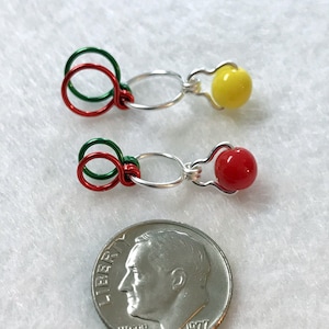 May include: Two silver wire jewelry findings with red, green, and yellow beads. The findings are about the size of a US dime.