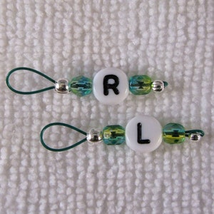May include: Two green and white beaded zipper pulls with silver beads and letter charms. The top pull has the letter "R" and the bottom pull has the letter "L".