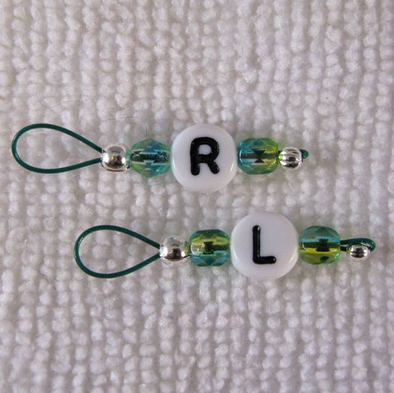 May include: Two green and white beaded zipper pulls with silver beads and letter charms. The top pull has the letter "R" and the bottom pull has the letter "L".