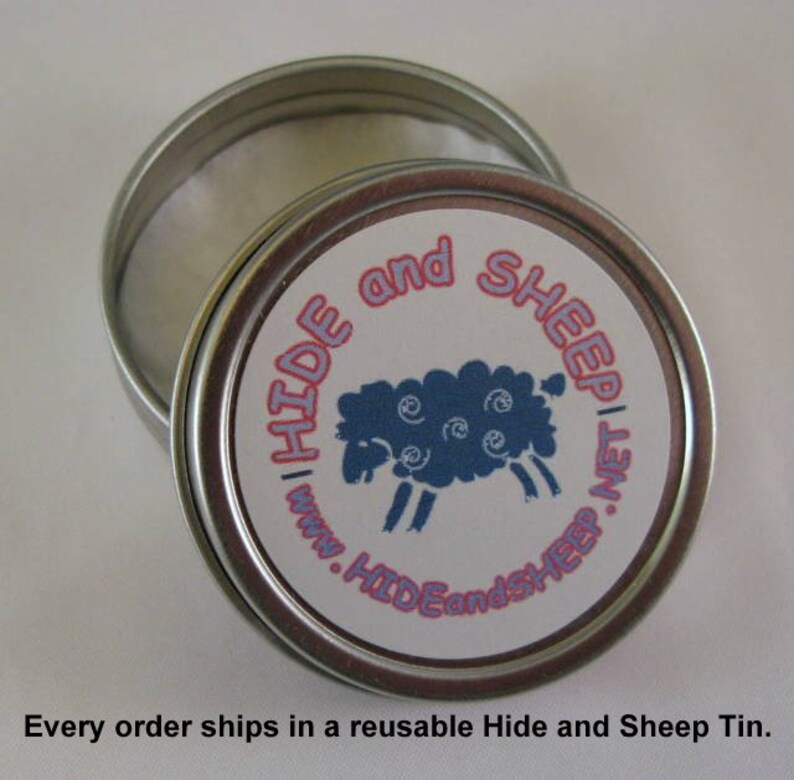 May include: A silver tin with a white label and pink lettering that reads "HIDE and SHEEP" with a blue sheep illustration. The tin is open and the inside is lined with white paper.