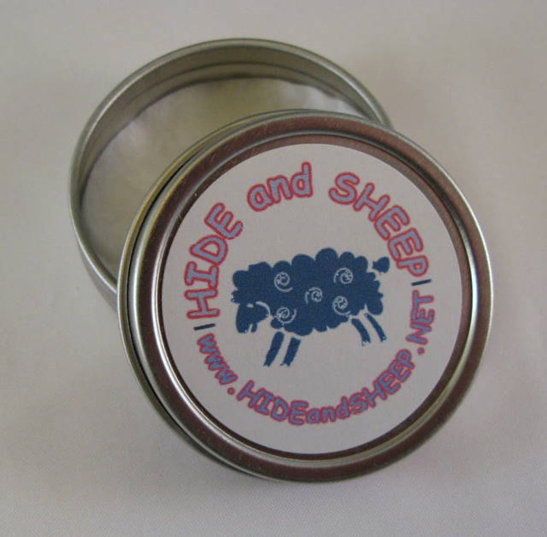 May include: A silver tin with a white lid and a blue and white sheep illustration on the label. The label reads "Hide and Sheep | www.HideandSheep.net".