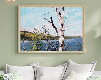 May include: A framed matte poster featuring an impressionistic landscape painting. The artwork depicts a birch tree with white bark and dark branches, a lake, and a blue sky. The painting is in a wooden frame and is displayed above white pillows.