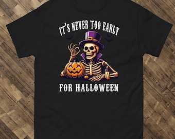 May include: Black t-shirt featuring a skeleton wearing a purple top hat and cape, holding an orange pumpkin. The text "IT'S NEVER TOO EARLY FOR HALLOWEEN" is printed above and below the graphic. A Halloween-themed graphic tee.