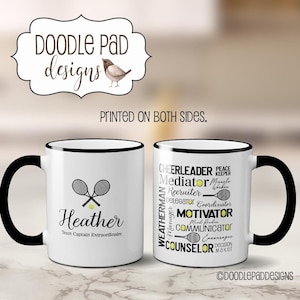 May include: White ceramic coffee mug with a black rim and handle. The mug has a tennis racket and ball design with the text "Heather Team Captain Extraordinaire". The other side of the mug has a black and white tennis racket design with the text "Cheerleader, Mediator, Recruiter, Delegator, Coordinator, Motivator, Mind Reader, Communicator, Encourager, Counselor, Decision Maker, Weatherman, Manager, Peace Keeper, Miracle Worker". The text "Doodle Pad Designs" is at the bottom of the mug.