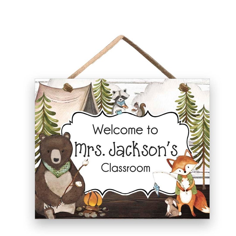 May include: Wooden classroom sign featuring woodland animals and the text "Welcome to Mrs. Jackson's Classroom." The sign includes a bear, fox, raccoon, and squirrel, with a camping theme and a rope for hanging.