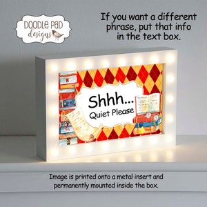May include: A white light-up sign with a red and yellow checkered background. The sign says "Shhh... Quiet Please" and features a stack of books with a scroll.