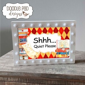 May include: A white sign with a light-up border featuring a stack of books, a scroll, and a red and yellow diamond pattern. The sign reads "Shhh... Quiet Please".
