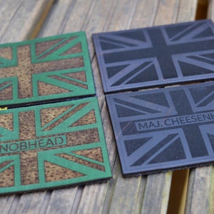 May include: Four leather coasters featuring a Union Jack design. Two coasters are green and brown with the text "KNOBHEAD" and the other two are black with the text "MAJ. CHEESENHAM".