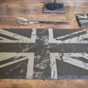 May include: A slate placemat featuring a distressed Union Jack design. The placemat is grey with white accents.