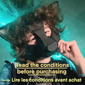 May include: A black wolf mask with matching ears. The mask covers the lower face and nose. The text "Read the conditions before purchasing" is displayed in yellow, with a French translation below.