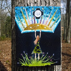May include: A mosaic artwork depicting a woman holding up a blue and gold sky with a crescent moon and stars. The woman is wearing a green dress and has red hair. The background is black with a swirling pattern.