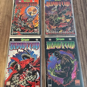 May include: Four Spawn Blood Feud comic books in protective sleeves. The covers feature vibrant illustrations of Spawn characters in action, with bold lettering and dynamic artwork. The color palette includes red, orange, blue, and green, creating a striking visual impact.