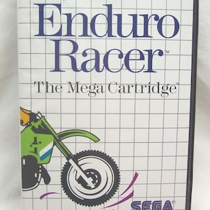 May include: A SEGA Enduro Racer video game cartridge. The white box features the game title in blue, a green and white motorcycle graphic, and the SEGA logo. The text "For One Player" and "The Mega Cartridge" are also displayed.
