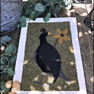 May include: A needlepoint artwork of a black bird with a yellow flower in its beak, on a green background. The artwork is titled "Olde James" and signed "2018 - Harvest Folk Art - D. Frost".
