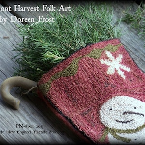 May include: A red, green, and white wool stocking with a snowman design. The stocking is filled with evergreen branches and has a wooden hook.