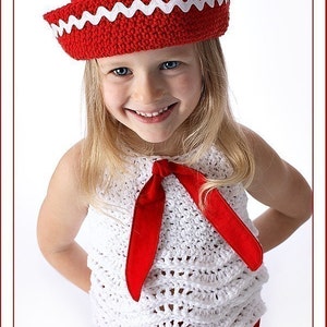 Może przedstawiać: Mała dziewczynka w białej koronkowej bluzeczce z czerwoną koronkowa kokardką i czerwonym koronkowa kapeluszem z białym wykończeniem.