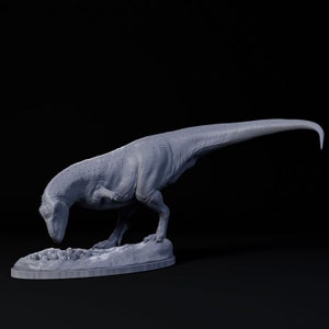 May include: A grey, detailed dinosaur figurine standing on a base with a nest of eggs. The dinosaur is in a crouching position, with its head lowered as if it is looking at the eggs.