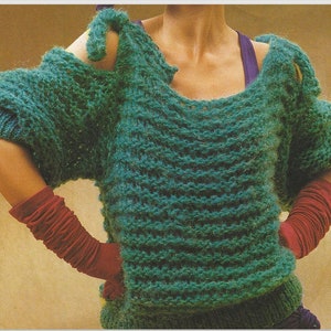 May include: A teal green knitted sweater with short sleeves and a wide neckline. The sweater features a textured, ribbed design and is worn with red arm warmers. The sleeves have a unique cut-out design.
