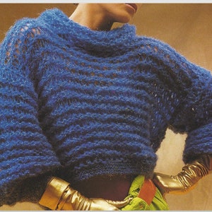 May include: A blue knitted jumper with a loose fit and a textured pattern. The jumper has a high neckline and long sleeves.