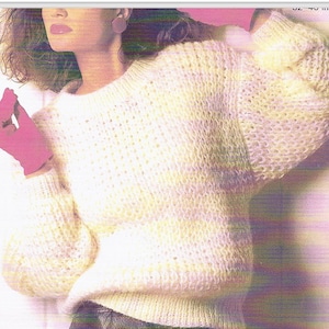 May include: A white knitted jumper with a round neckline and long sleeves. The jumper has a loose fit and a textured knit.