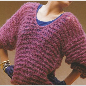 May include: A loose-fitting, pink knitted jumper with a V-neck and a lacy pattern.