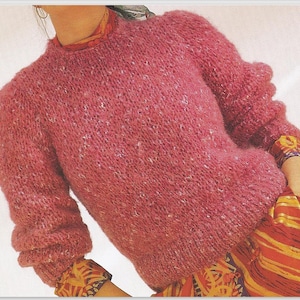 May include: A pink fluffy jumper with a round neckline. The jumper is made of a soft, fluffy yarn.