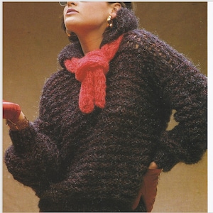 May include: A dark brown fuzzy sweater with a red scarf tied around the neck. The sweater has a loose fit and long sleeves.