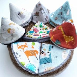 Può includere: Un set di nove bavaglini per bambini colorati con vari motivi di animali e veicoli. I bavaglini sono realizzati in tessuto morbido e hanno una fodera in pile grigia.