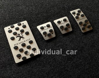 May include: Set of four silver car pedal covers with black rubber pads. The covers feature the Peugeot logo and the word "PEUGEOT" printed in white.