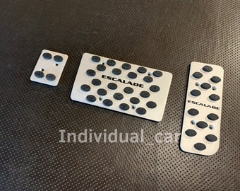 Op de afbeelding: Drie zilveren metalen auto-pedaalkappen met zwarte rubberen inzetstukken. De kappen hebben de tekst "ESCALADE" erop gedrukt.