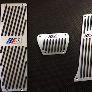 May include: Set of three silver car pedal covers with black rubber inserts and the BMW M logo.