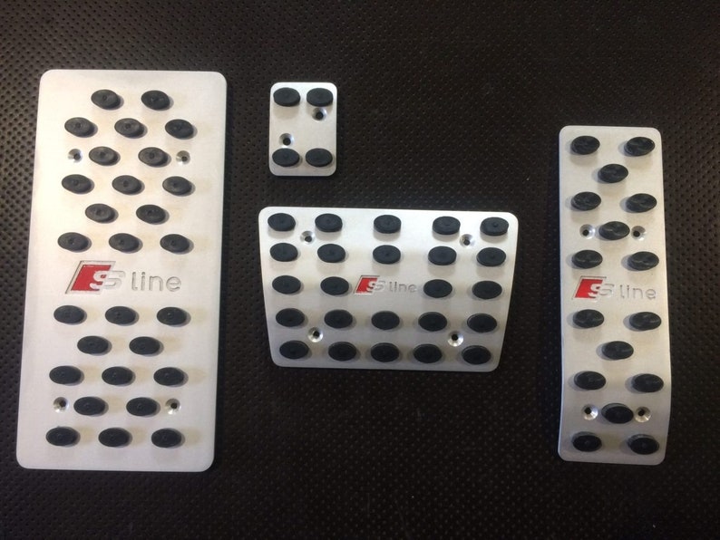 May include: Set of four silver-colored car pedal covers with black rubber studs for grip. Each pedal cover has the red and white "S line" logo. The set includes an accelerator, brake, clutch, and footrest cover.