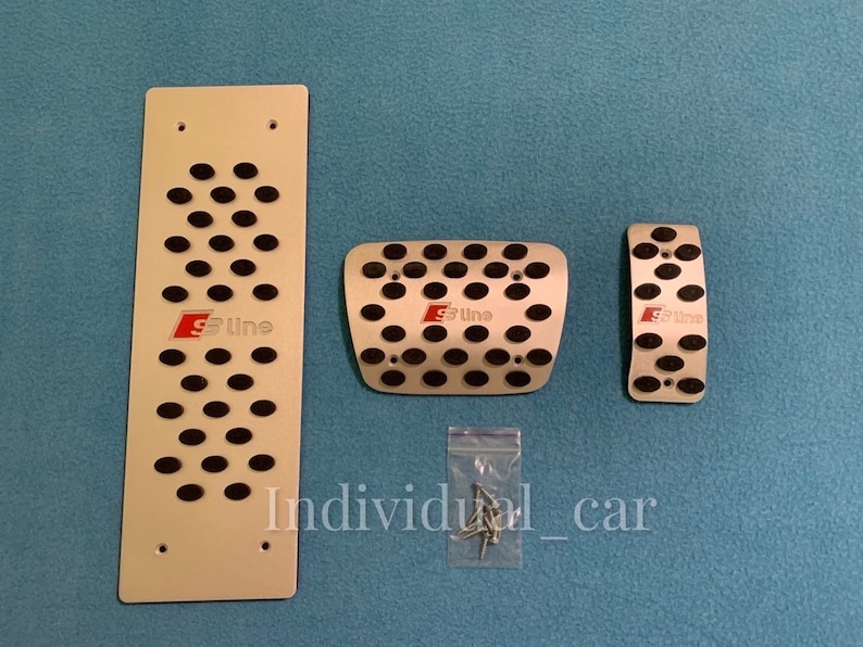 May include: Set of three silver-colored car pedal covers with black rubber inserts. The covers have the text "S Line" in red. Includes a long rectangular plate, a square plate, and a smaller rectangular plate. The text "Individual_car" is visible.