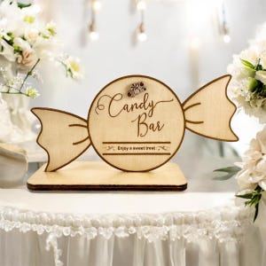 Op de afbeelding: Houten bord voor een snoepbar in de vorm van een snoepje met de tekst "Candy Bar" en "Enjoy a sweet treat".