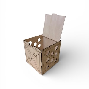 Puede incluir: Una caja de madera con tapa con bisagras y recortes circulares decorativos. La caja tiene un diseño tipo caja con soportes cruzados diagonales en los lados. La caja está hecha de madera de color claro y se encuentra sobre una superficie blanca.