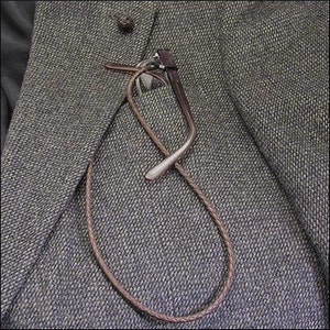 May include: A yellow metal tile lifter tool with a wooden handle and adjustable arms, designed to lift and move tiles. The tool is resting on a wooden surface.