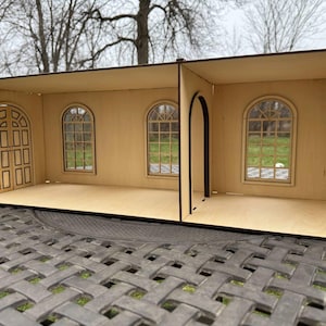 May include: A wooden dollhouse with a light brown finish. It has a door, arched windows, and an arched doorway. The dollhouse is divided into two sections and is rectangular in shape.