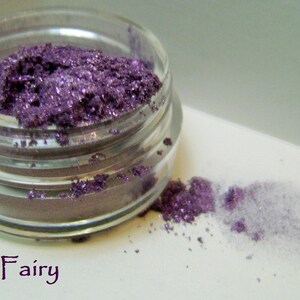 May include: A small glass jar filled with purple glitter eyeshadow. The jar is labeled "Purple Fairy".
